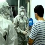 Medical personnel wearing protectice suits interact with two patients (R on bed and standing) tested positive to the coronavirus in an isolation room at Cho Ray hospital in Ho Chi Minh City on January 23, 2020. - Two Chinese nationals in Vietnam have tested positive for the SARS-like coronavirus and are being treated in hospital, officials said on January 23. (Photo by STR / Vietnam News Agency / AFP)